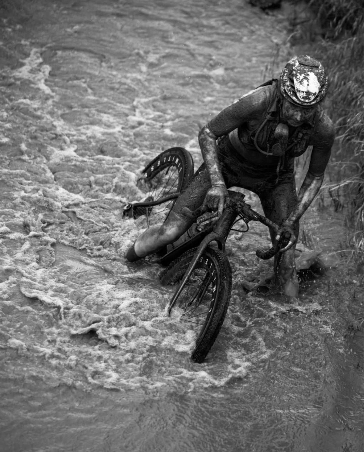 Ciclista cruzando un arroyo crecido con su bicicleta en Unbound Gravel 2026