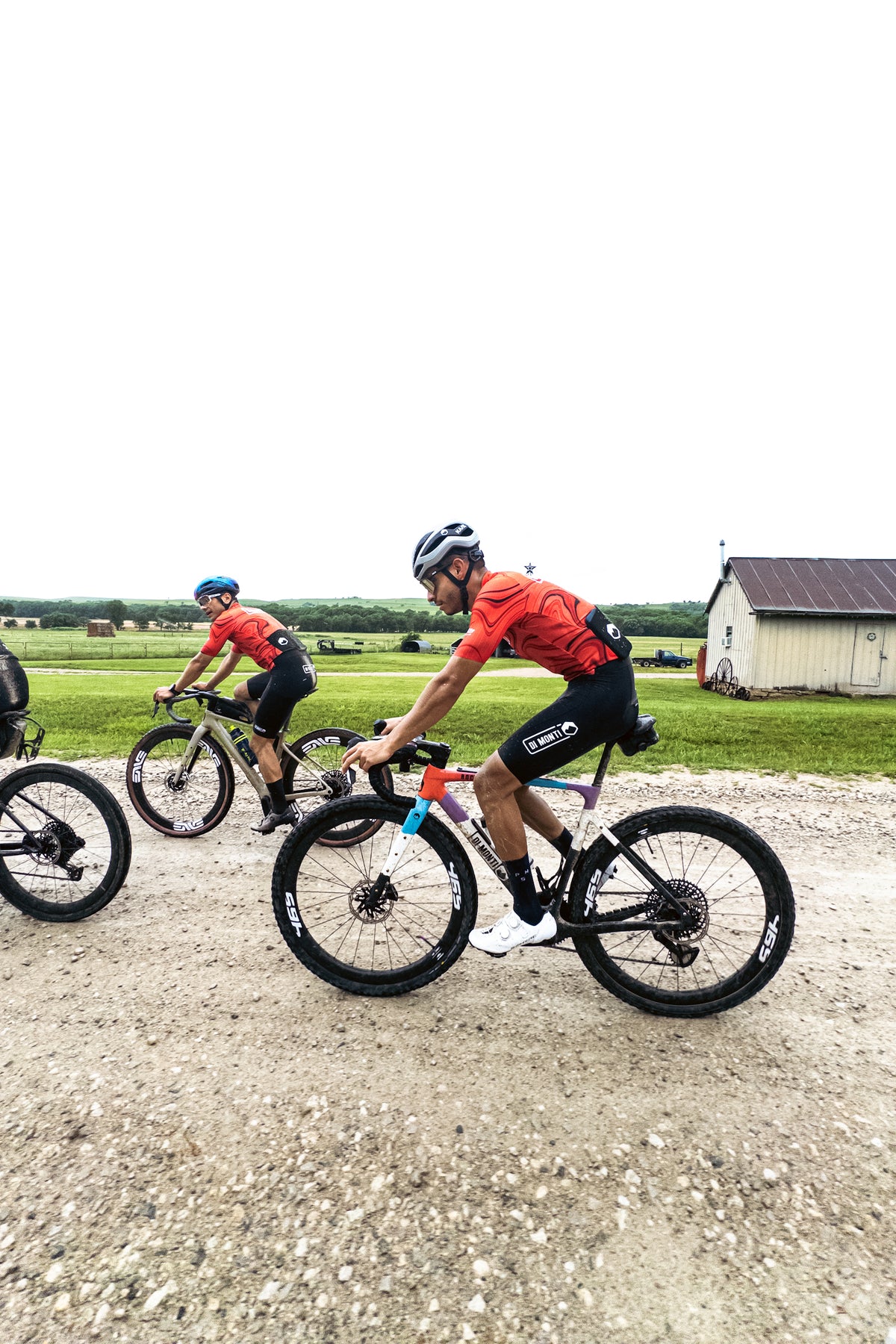 Ciclistas Di Monti rodando en gravel junto a un granero en Kansas, previa de Unbound 2026